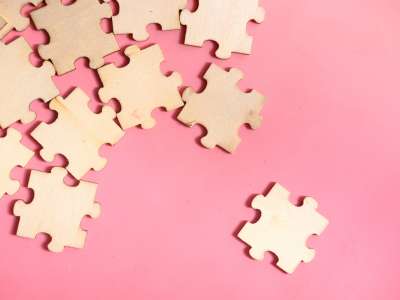 Puzzleteile aus Holz auf einem Pinken Hintergrund
