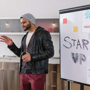Ein Junger Mann steht vor einem beschriebenen Präsentationshilfsmittel und übt seine Präsentation.