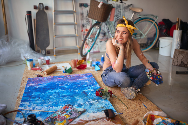 Junge Frau malt mit Freude in einem Atelier – Symbol für kreative Selbstverwirklichung im Single-Leben