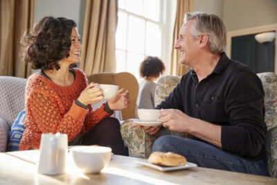 Mann und Frau mittleren Alters lachen beim Kaffee und genießen ein Gespräch