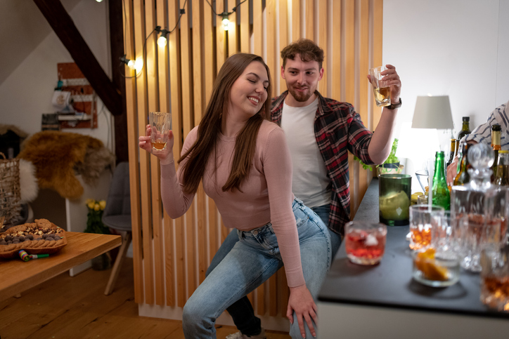 Ein glückliches Paar feiert bei einem Date zu Hause. Das Bild dient als Titelbild für den News-Artikel zum Tinder Größenfilter und symbolisiert das Ziel der Online-Partnersuche: eine echte Verbindung zu finden.