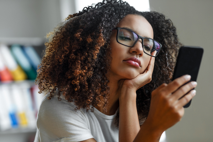 Frau gelangweilt beim Scrollen auf dem Smartphone, genervt von Dating-Apps