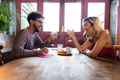 Glückliches Paar lacht und stößt mit Gläsern an – Hinge Dating App für echte Verbindungen