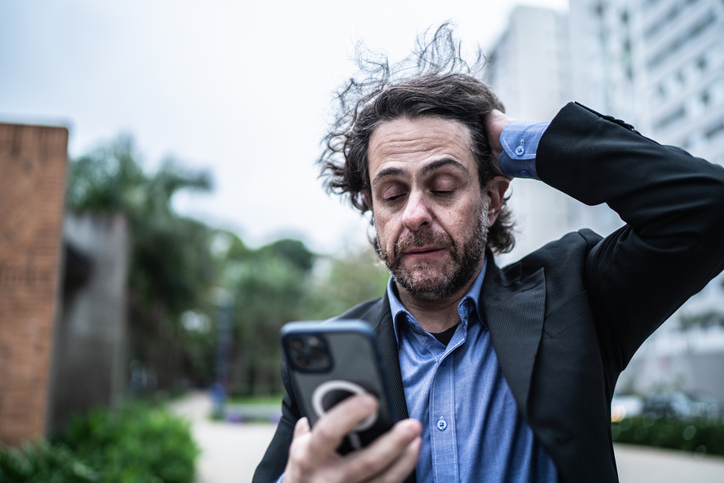 Mann mit besorgtem Ausdruck blickt auf Smartphone nach Datenleck.