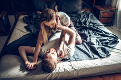 Paar lacht und umarmt sich im Bett – Tinder für schnelle Kontakte