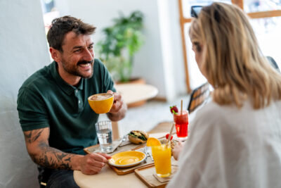 Paar beim ersten Date lacht und unterhält sich angeregt bei Kaffee und Drinks im Café