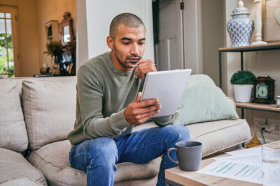 Ein Mann sitzt auf dem Sofa, schaut konzentriert auf sein Tablet und macht einen langen Persönlichkeitstest für eine Dating-App.