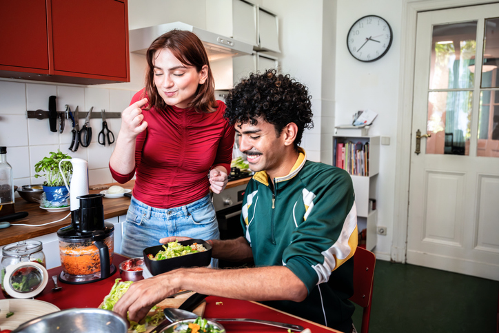 Zwei Freund:innen kochen gemeinsam in der Küche und lachen – Freundschaft, gemeinsame Zeit und echte Nähe im Alltag.