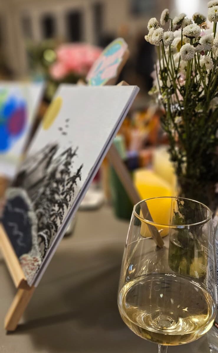 Weißweinglas vor Staffelei und Leinwand bei einem kreativen Paint-&-Drink-Single-Event von Diner Date in München und Landshut