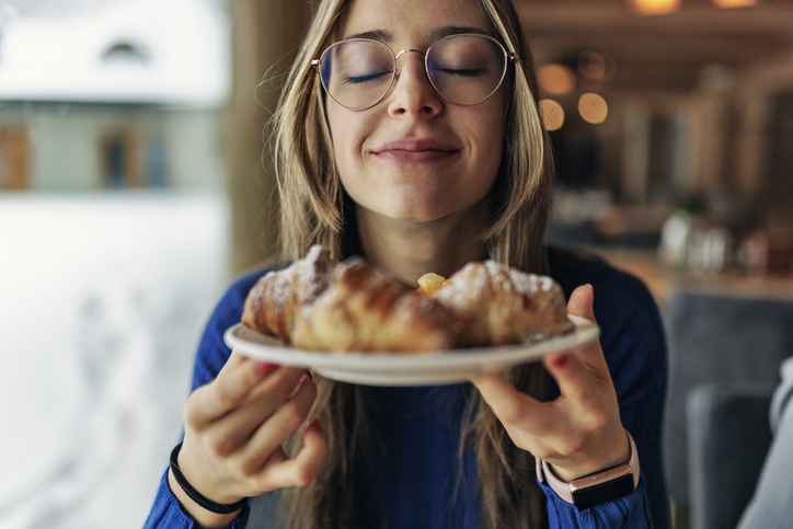 Junge Frau mit Gebäck auf einem Teller als symbolisches Bild für Eat Cake Day und die Freude an Kuchen und Süßem