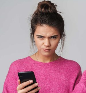 Falsche Werbung nervt. Eine Frau, die genervt schaut, weil sie etwas auf ihrem Handy gesehen hat.